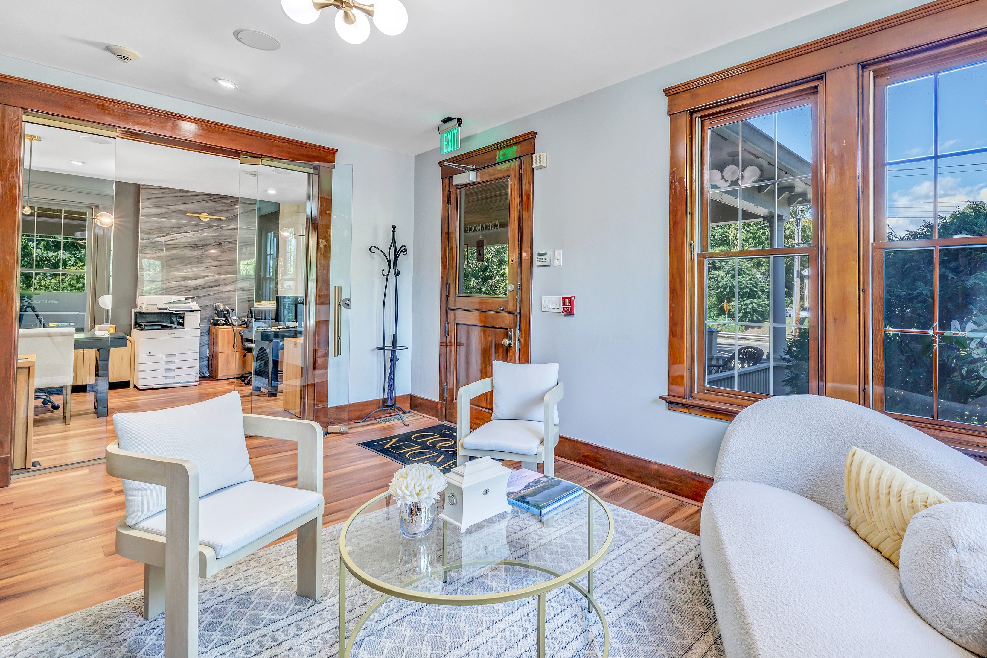 A living room with a glass table and white chairs.