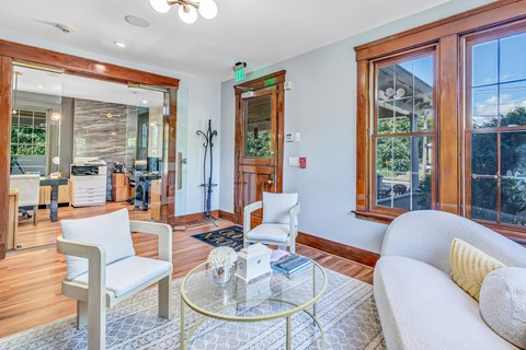 A living room with a glass table and white chairs.