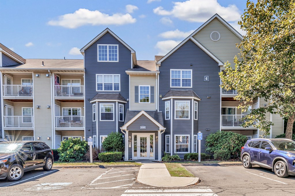 A large two-story building with a garage and a car parked in front.