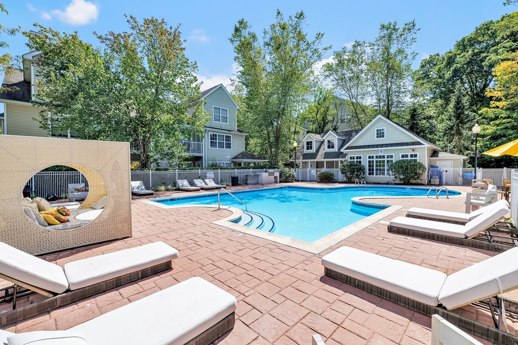 A pool area with a white chair and a yellow umbrella.