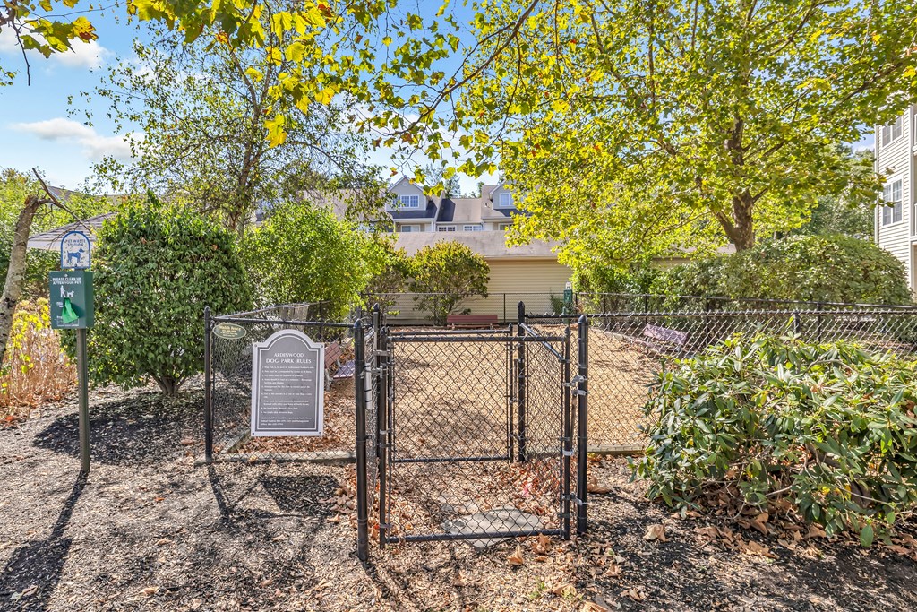 A sign in a fenced area with trees and bushes.