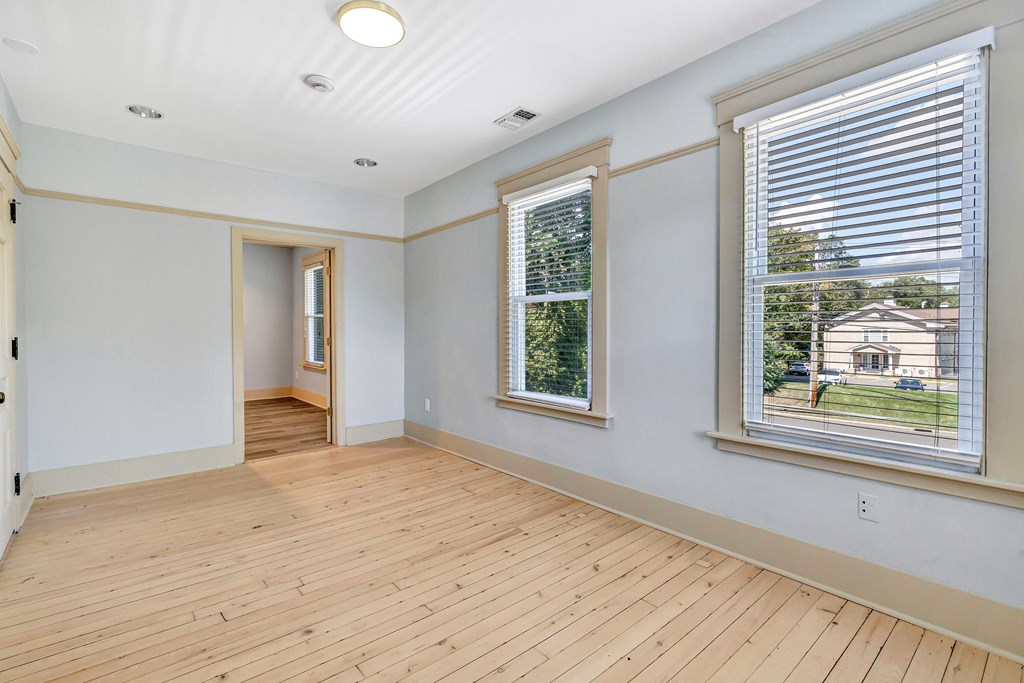 A room with wooden floors and two windows.