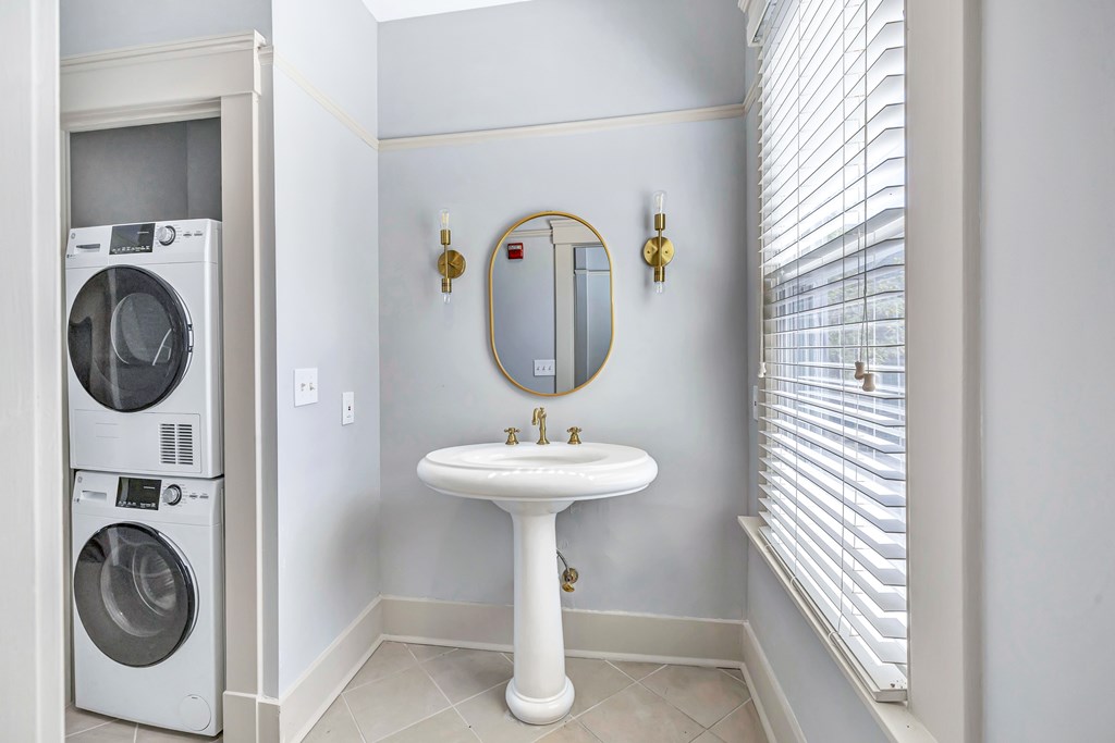 A white bathroom with a washer and dryer in the corner.