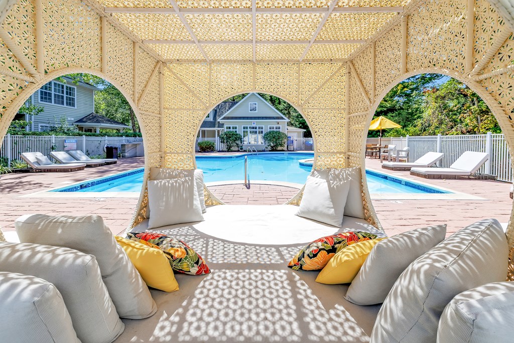 A pool area with a canopy and pillows.