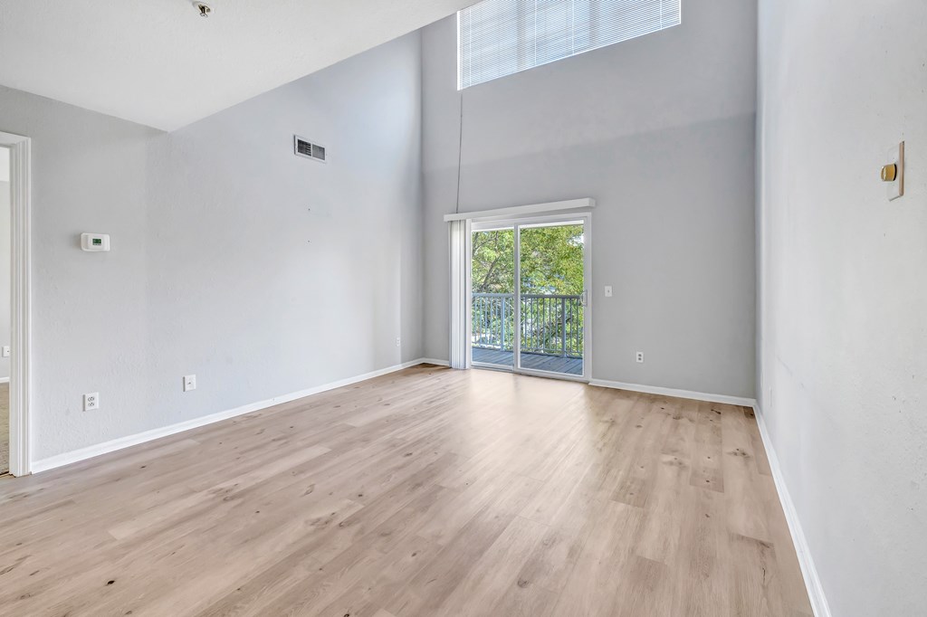 A room with wooden flooring and a sliding glass door leading to a balcony.