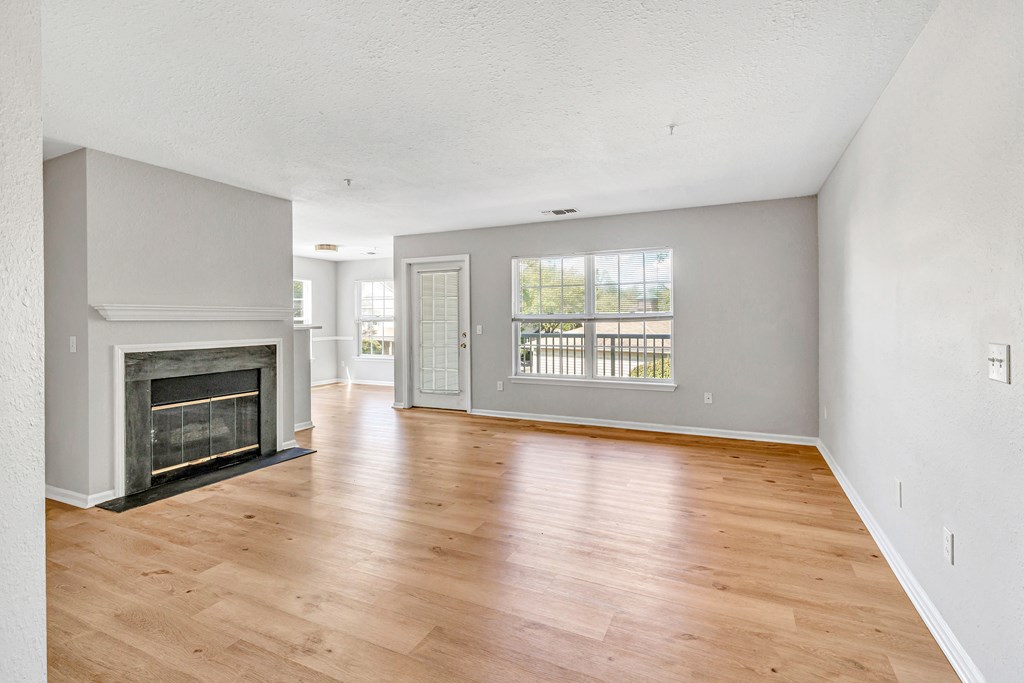 A spacious living room with a fireplace and hardwood floors.