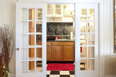 A kitchen with a red rug and a black and white checkered floor.