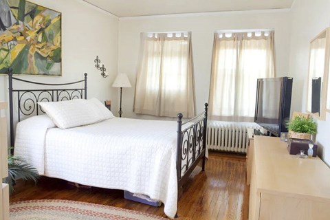 A bedroom with a white bedspread and a black metal bed frame.