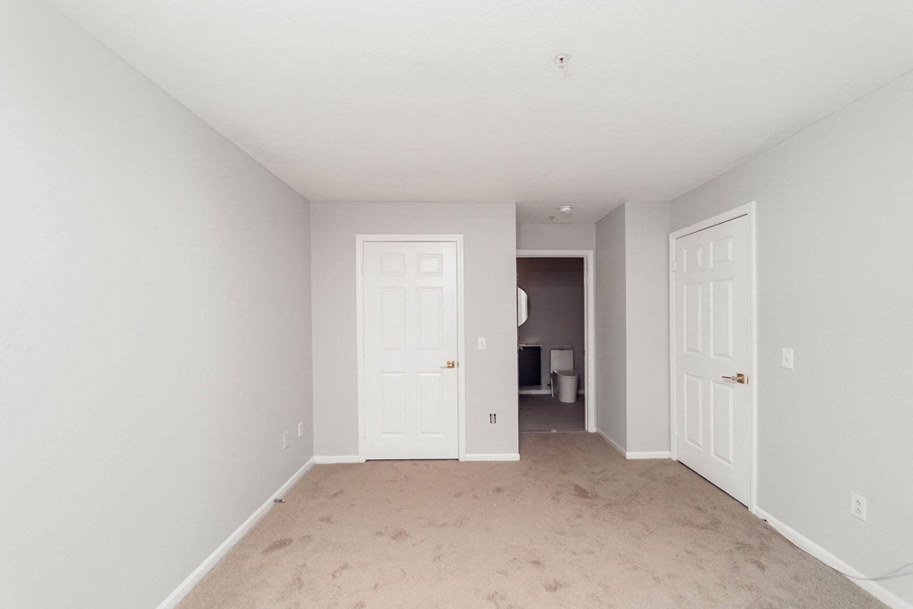 a bedroom with two doors and a carpeted floor