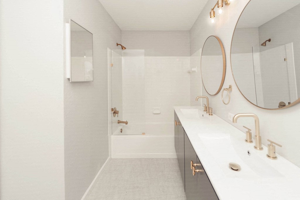 a white bathroom with a shower and a sink and a mirror