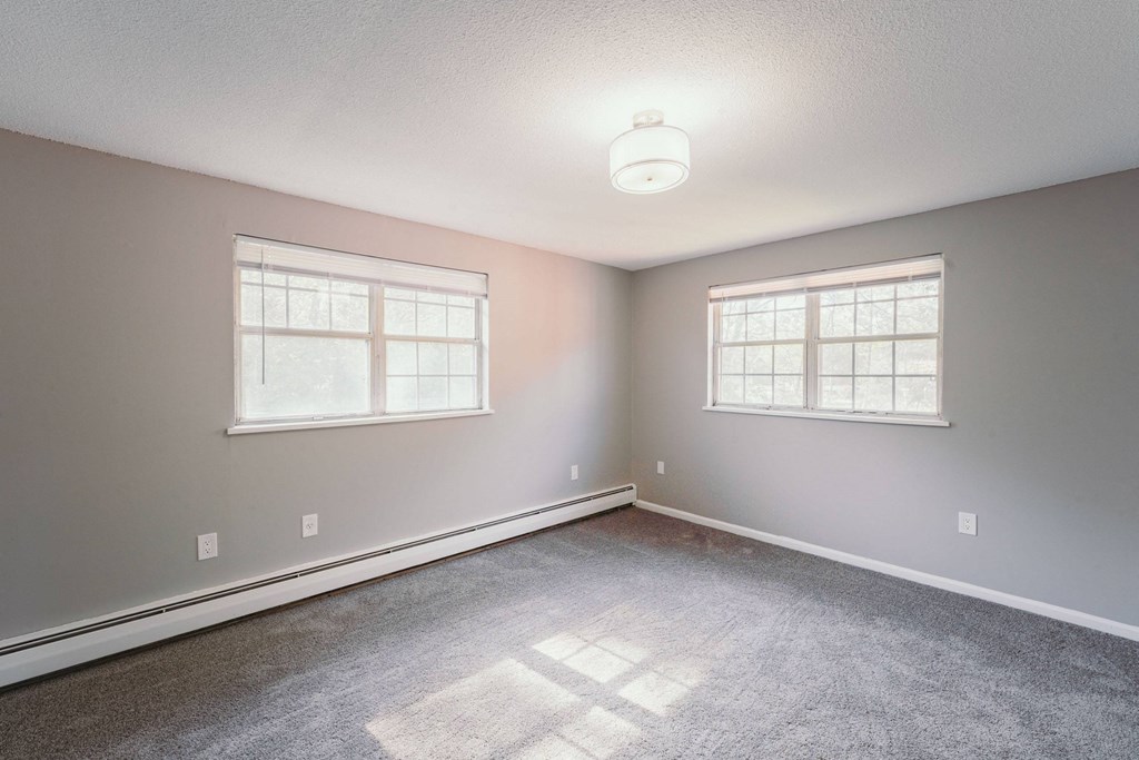 an empty bedroom with two windows and a carpeted floor at BAY SHORE APARTMENTS, EAST HAVEN, CT, 06512