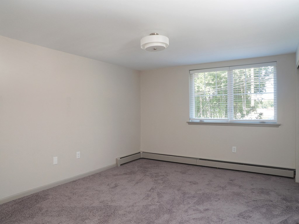 an empty living room with a window and carpet