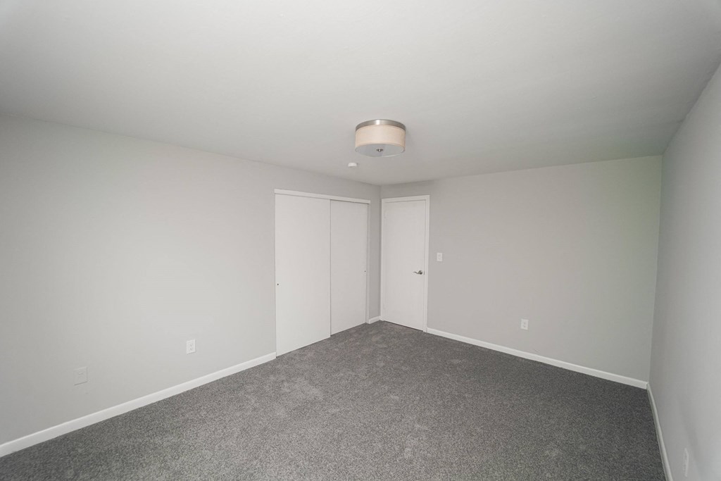 a bedroom with white walls and carpet and white doors