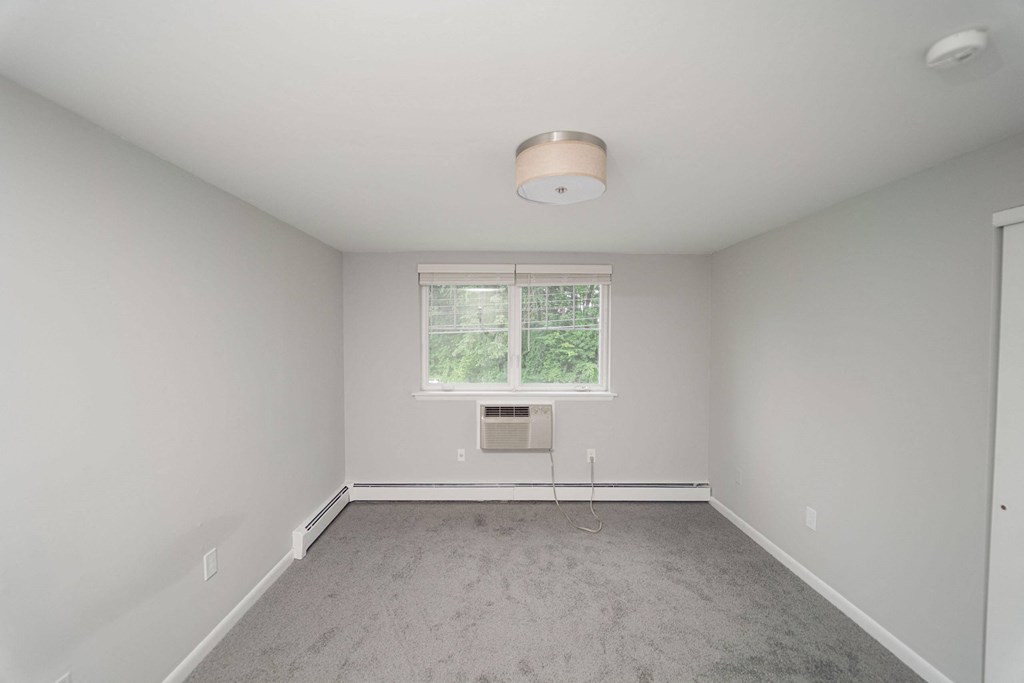an empty room with a window and white walls