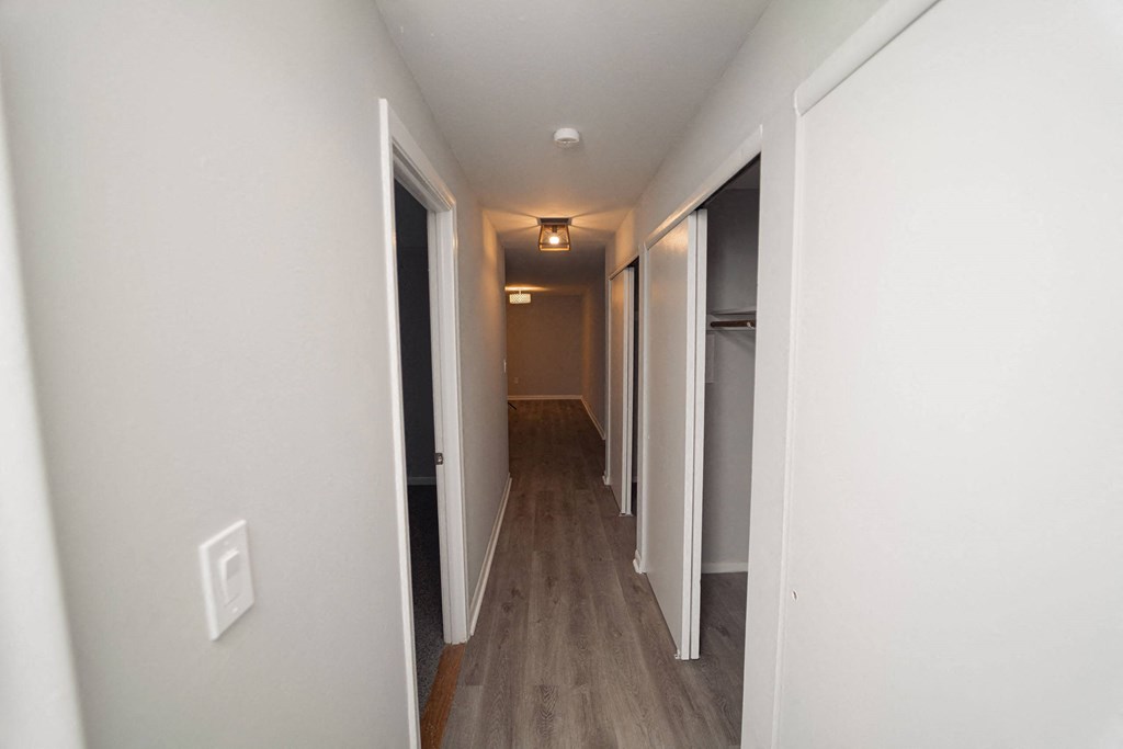 a pass through hallway in a new home with white walls and wood floors