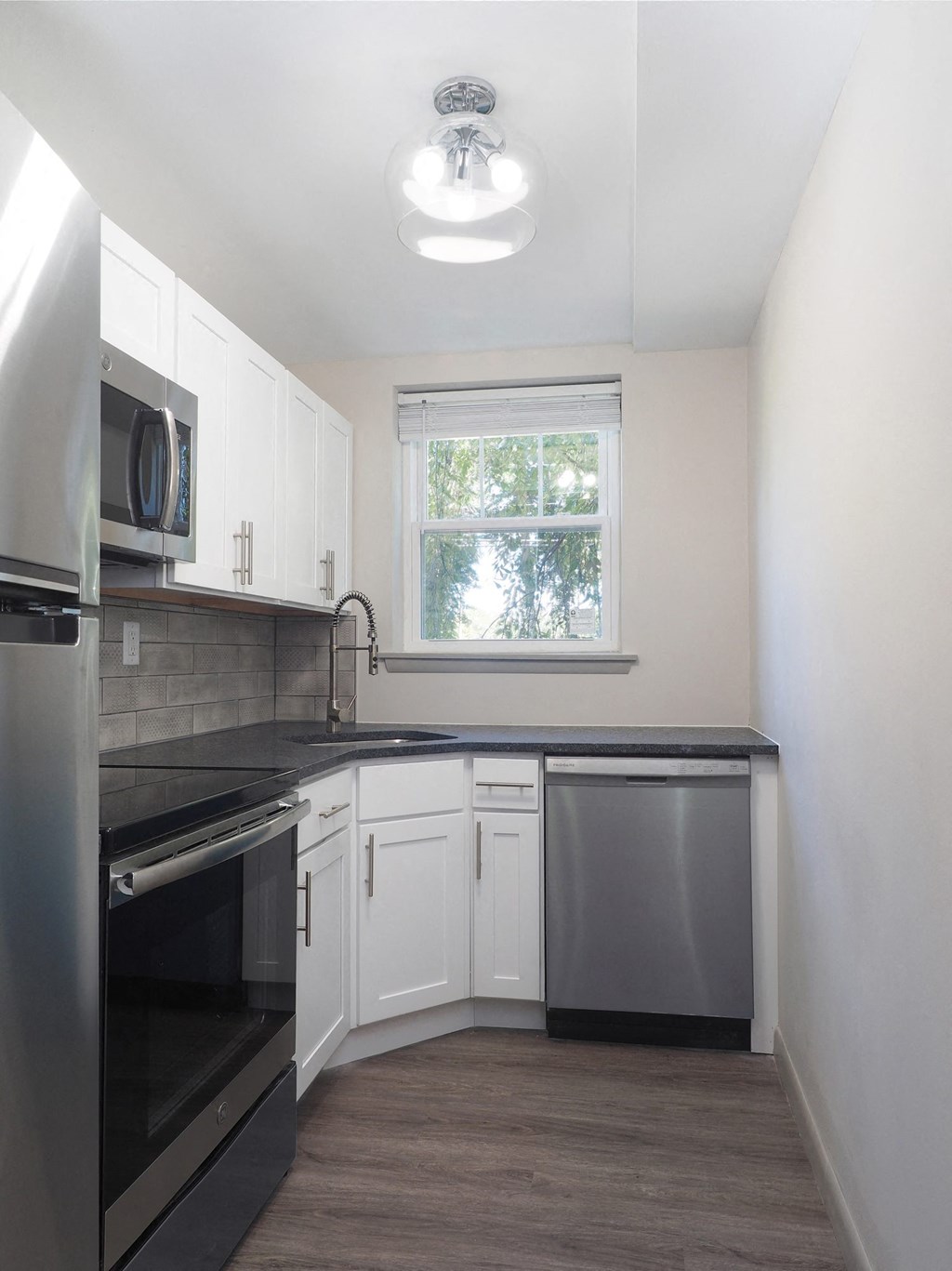 an empty kitchen with white cabinets and a black counter top