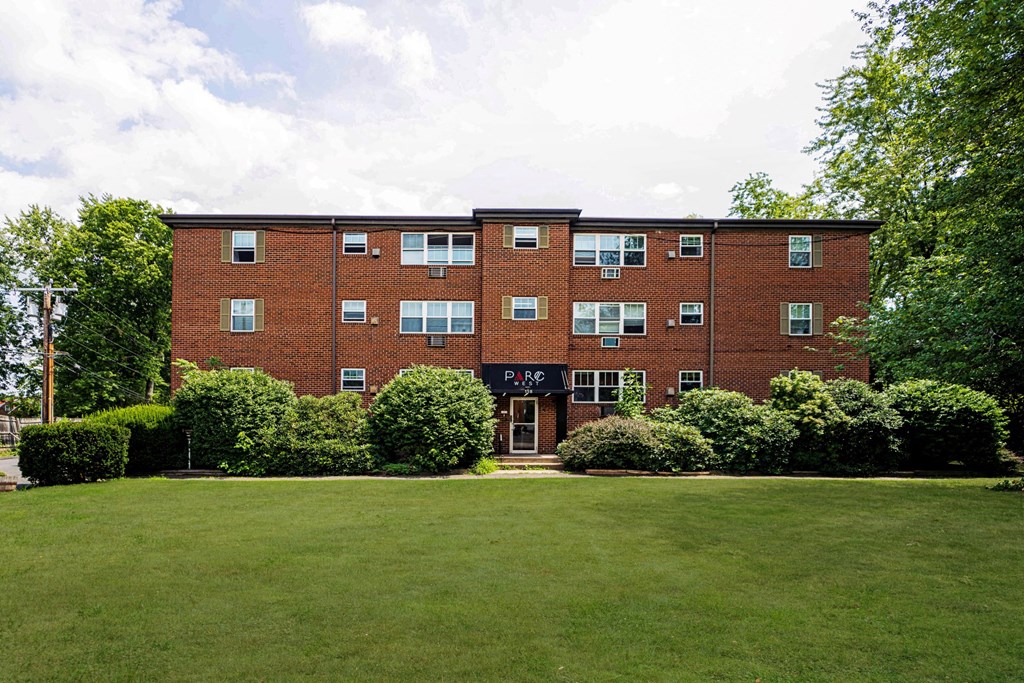 the front of a red brick building with a green lawn