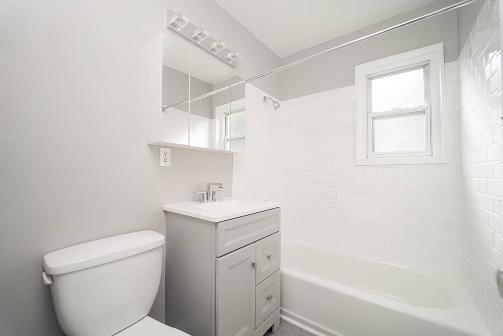 a white bathroom with a toilet and a tub at Encore 99, East Haven