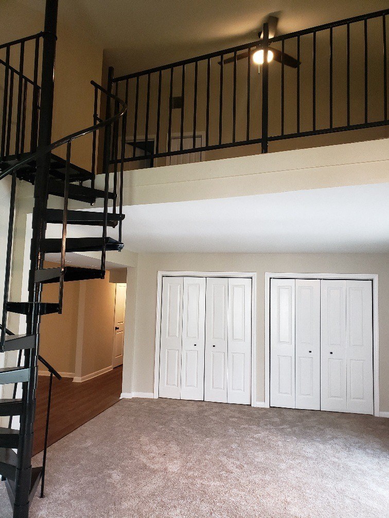 a loft in a home with a spiral staircase and white closets