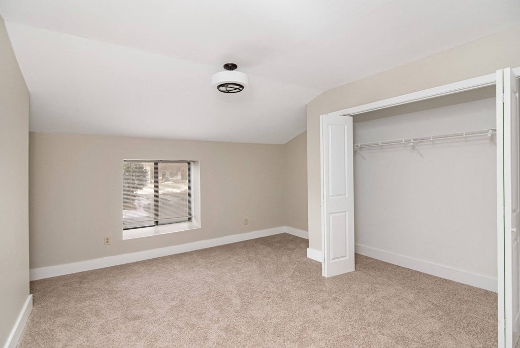 an empty bedroom with a closet and a window