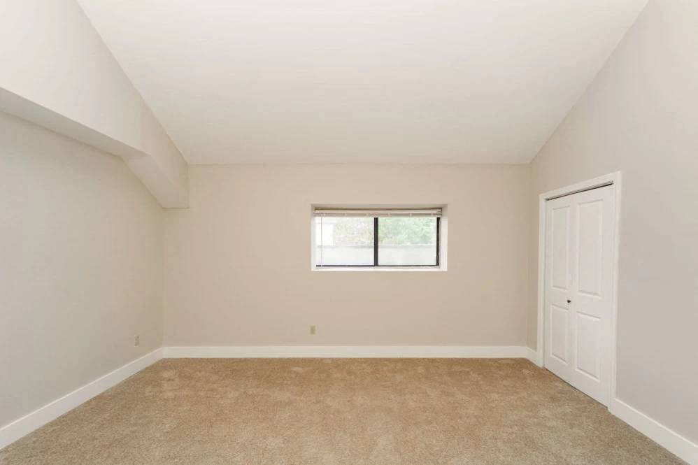 an empty bedroom with a window and a door