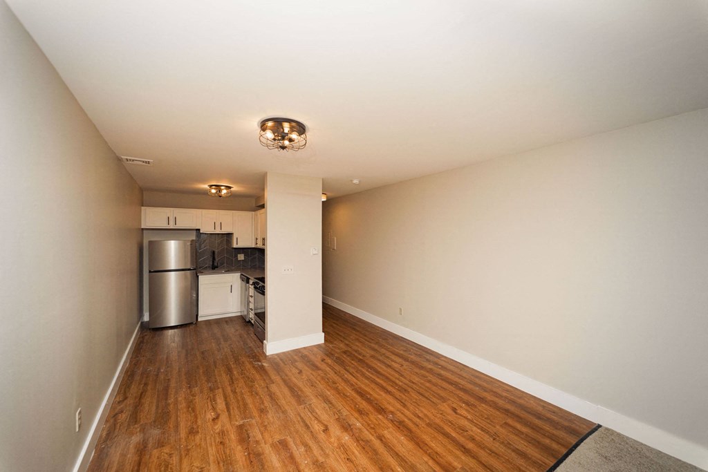 a renovated living room and kitchen with wood floors and white walls