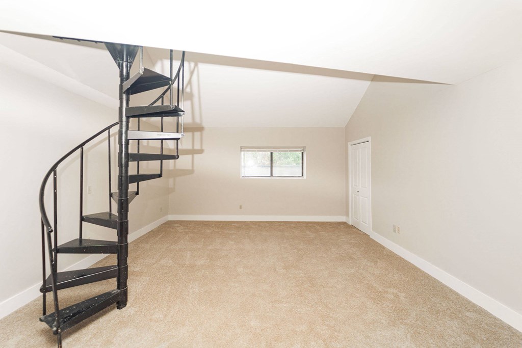 a small attic room with a spiral staircase and a window