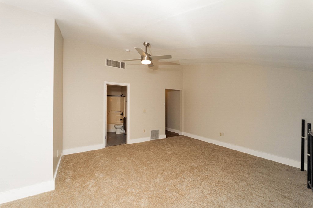 an empty living room with a ceiling fan