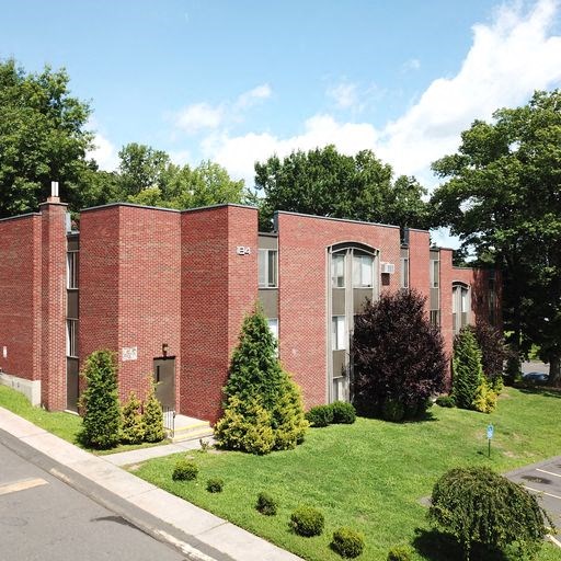 a red brick building with a lawn and trees