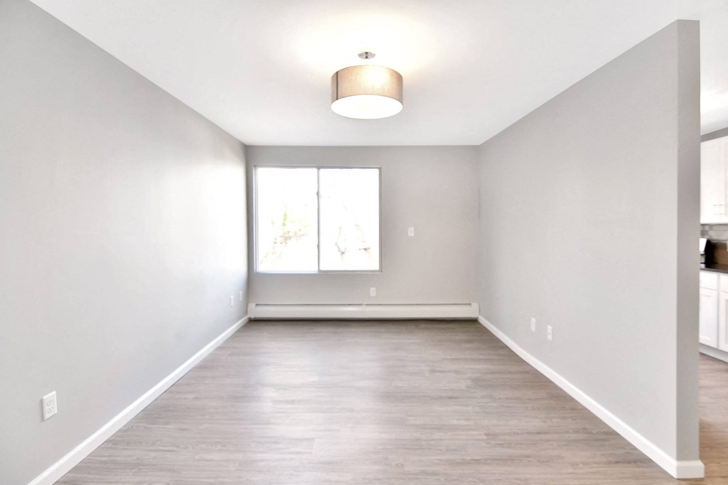 an empty living room with white walls and a window