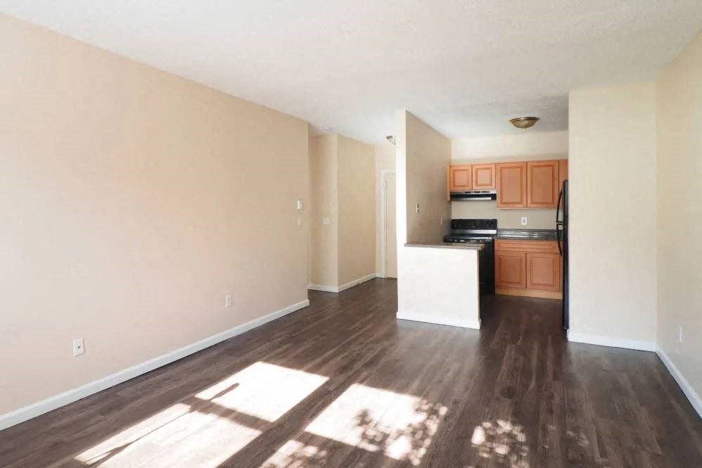 an empty living room and kitchen with wood floors