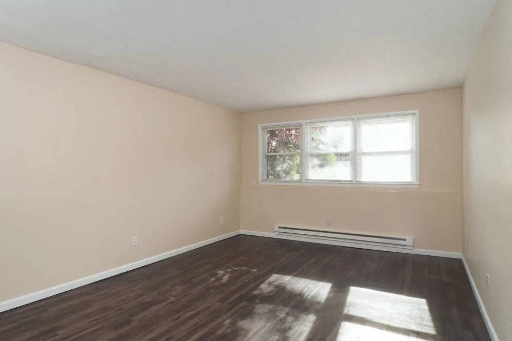 an empty living room with wood floors and a window