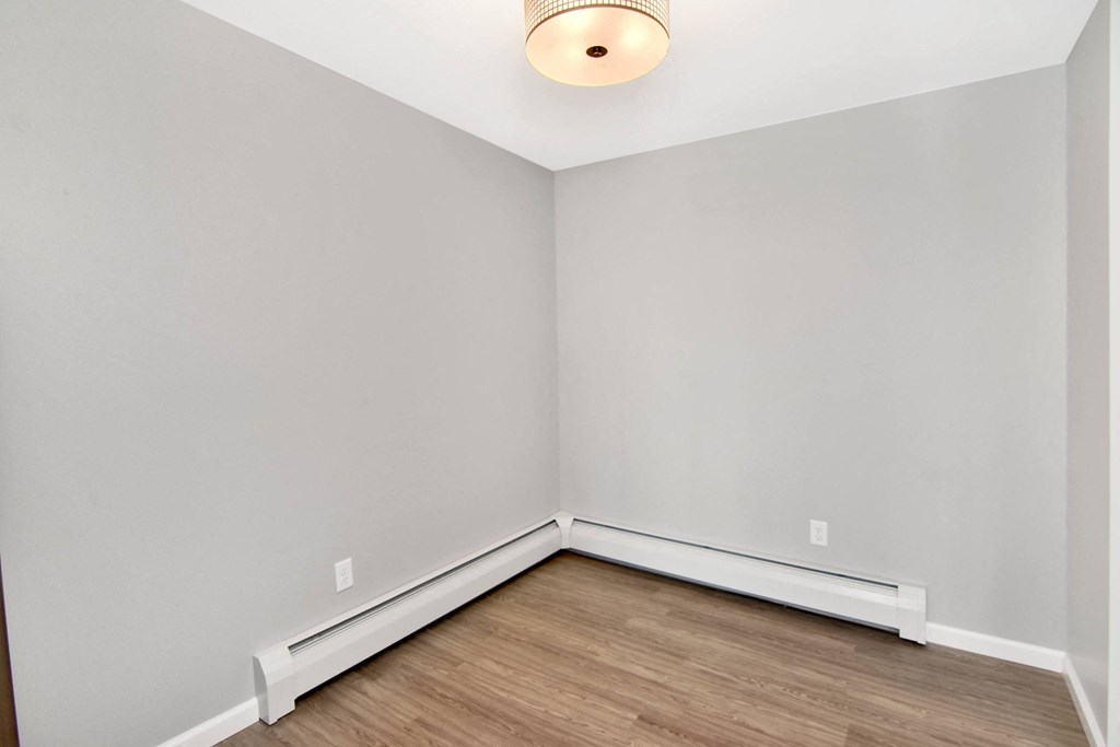 an empty room with white walls and wood flooring