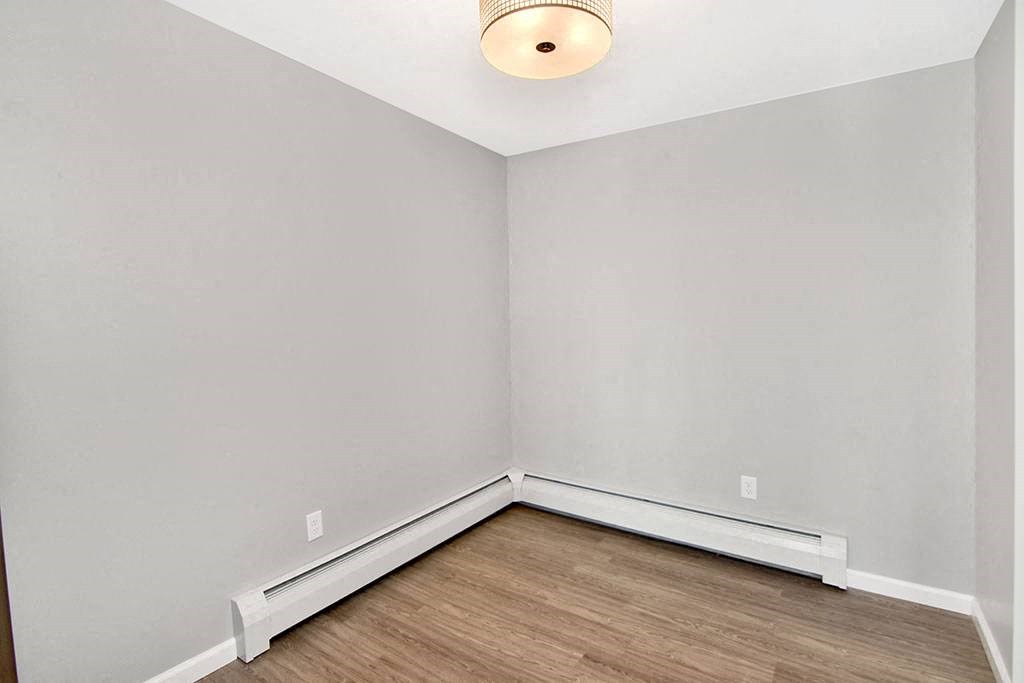 an empty room with white walls and wood floors