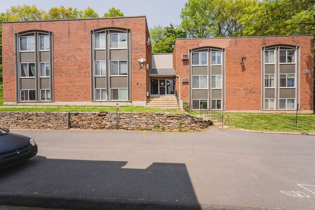 the front of a red brick building with a parking lot