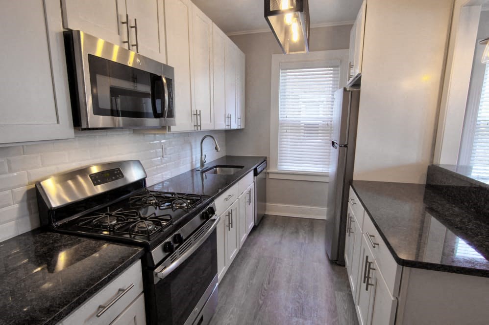 a kitchen with white cabinets and black counter tops