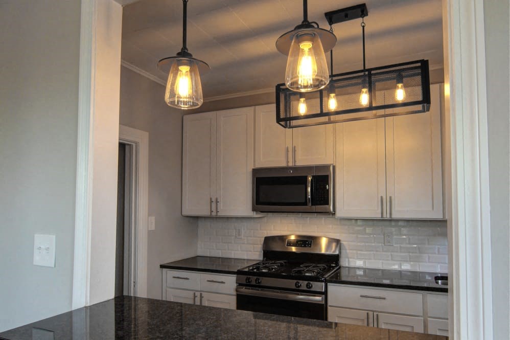 a kitchen with white cabinets and a stove and lights