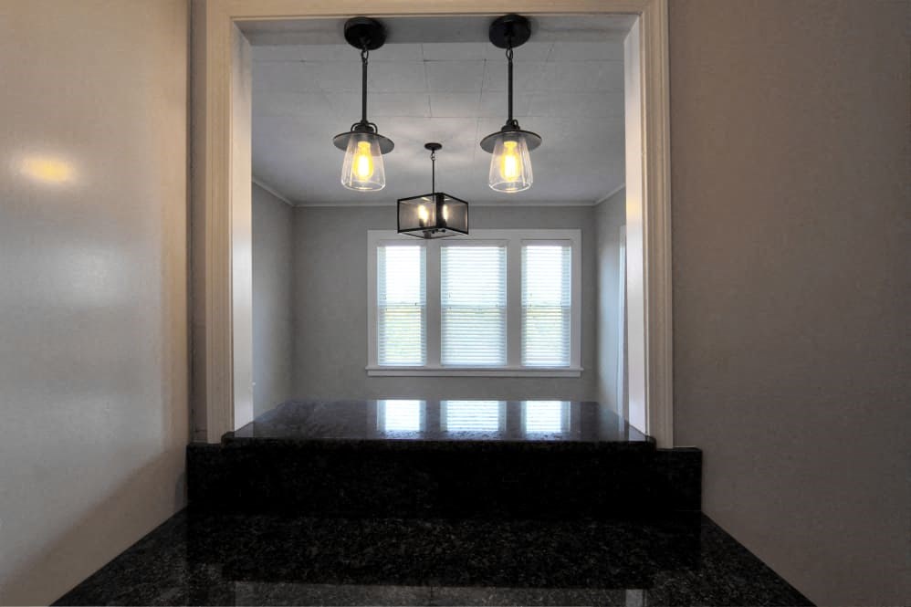 three lights hanging over a window in a room with a black counter