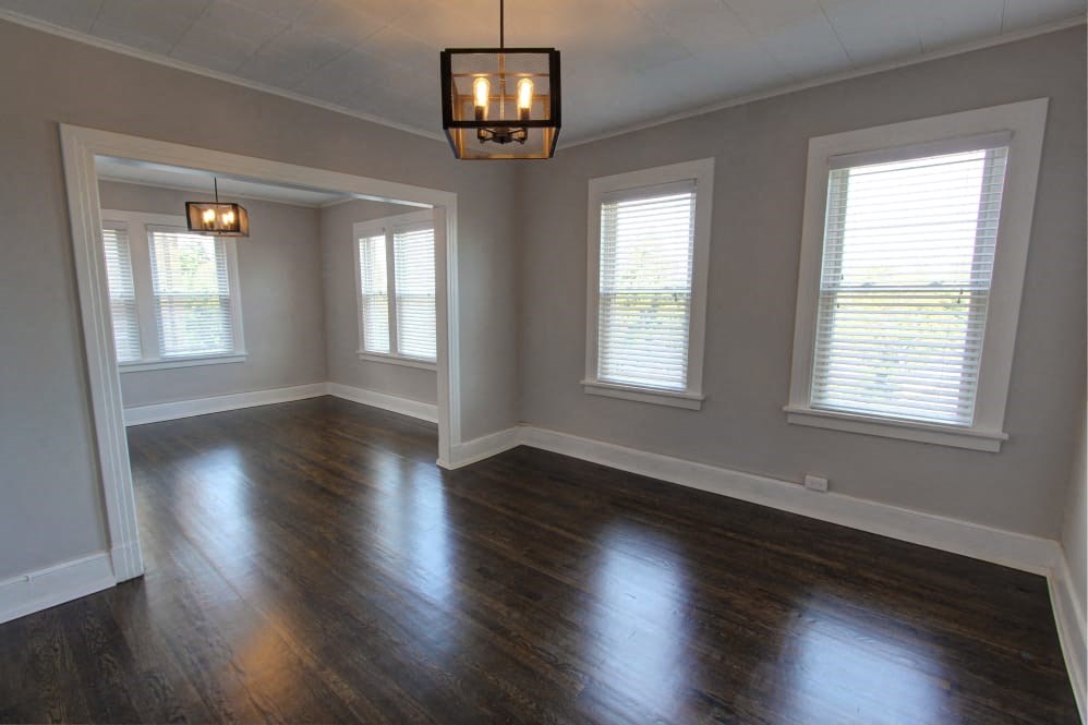 an empty living room with a hard wood floor and windows