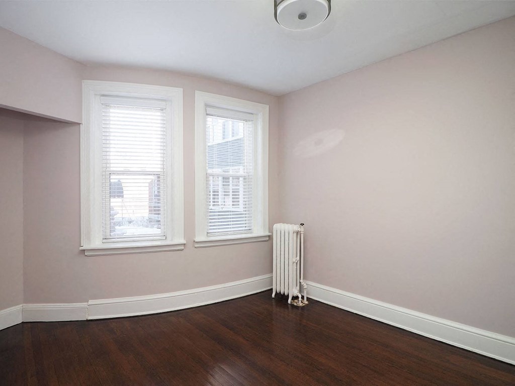 an empty room with a radiator and three windows