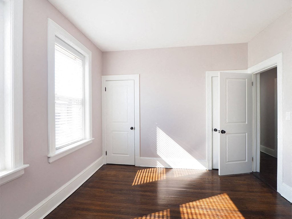 an empty room with a hard wood floor and white doors