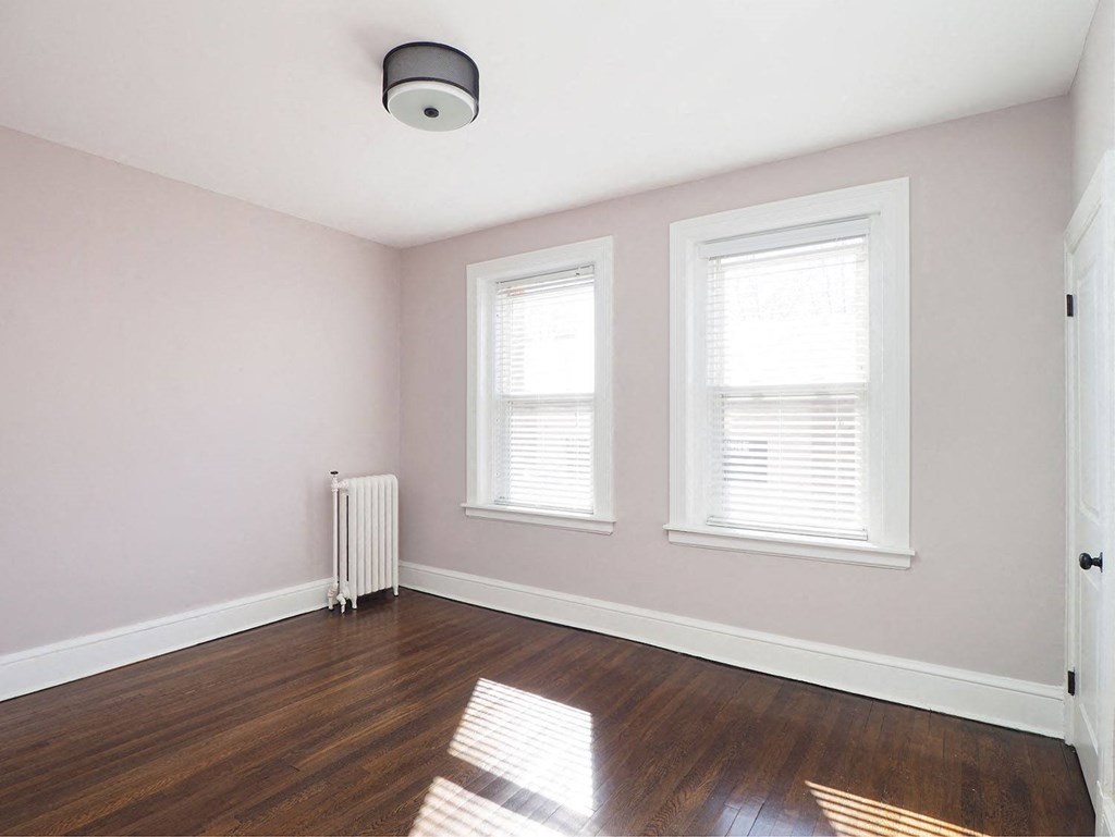 an empty room with two windows and wood floors