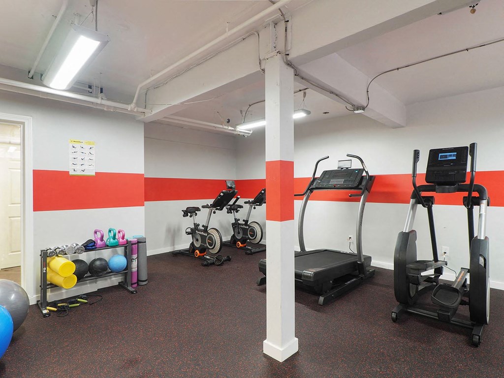 a gym with exercise equipment and a wall with a red and white stripe