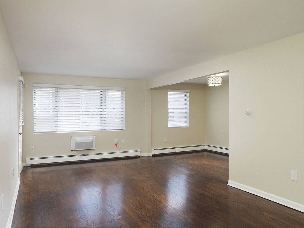 an empty living room with wood floors and a window