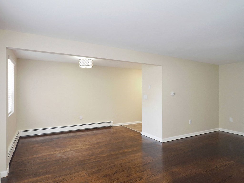an empty living room with wood floors and white walls