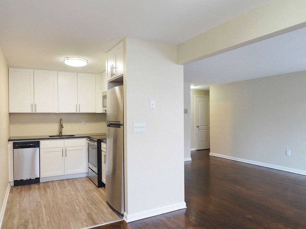 an empty kitchen with white cabinets and a stainless steel refrigerator