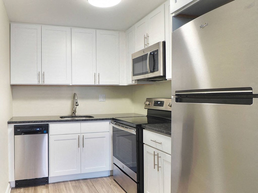 an empty kitchen with white cabinets and stainless steel appliances