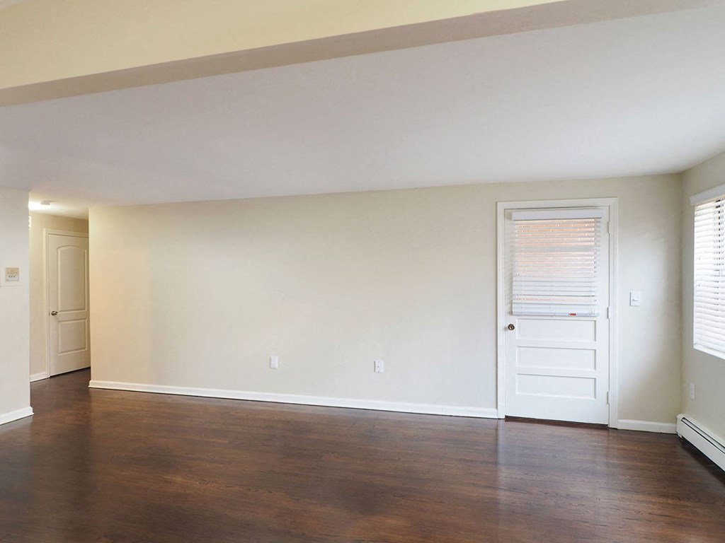 an empty living room with wood floors and a white door