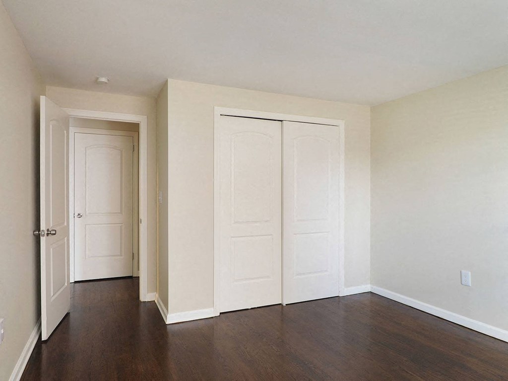an empty room with white doors and a wood floor
