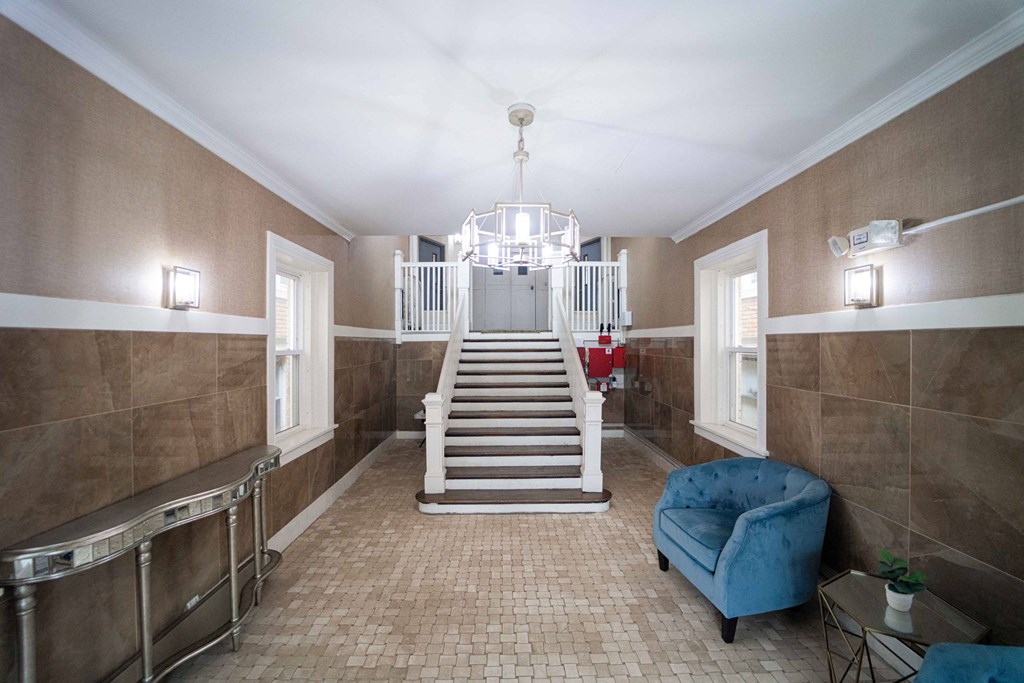 the lobby of a house with a staircase and a blue chair